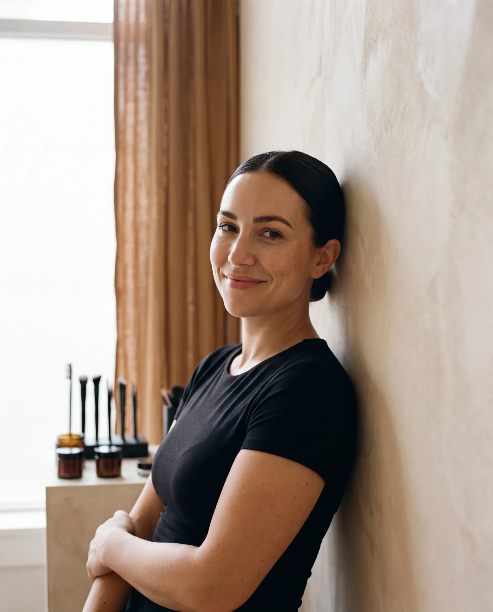 Ines Moreau leaning against the plaster wall of her studio